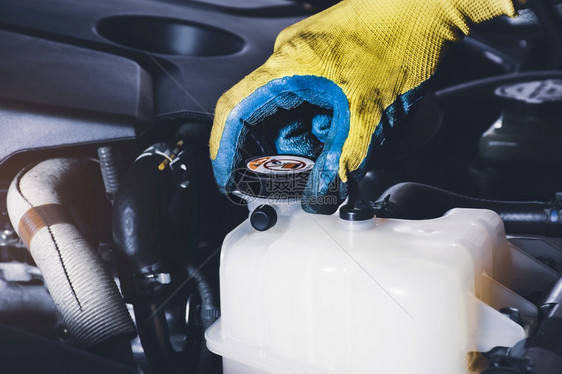 维护冷却器满的机械手打开或关闭汽车散热器冷却储水池的顶部以检查液体水平图片
