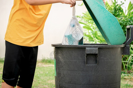 自然生态玻璃将垃圾丢入塑料袋扔进花园的垃圾桶图片