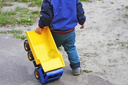 远足游戏娱乐小孩在路上拉着一辆大塑料车一个小孩在赛道上拖着一辆巨大的塑料车图片