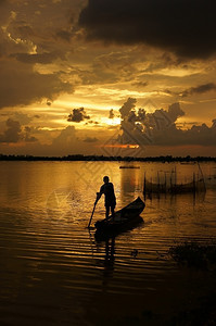 渔夫轮廓平静的人们站在划艇上日落时排船向河边的太阳前行图片