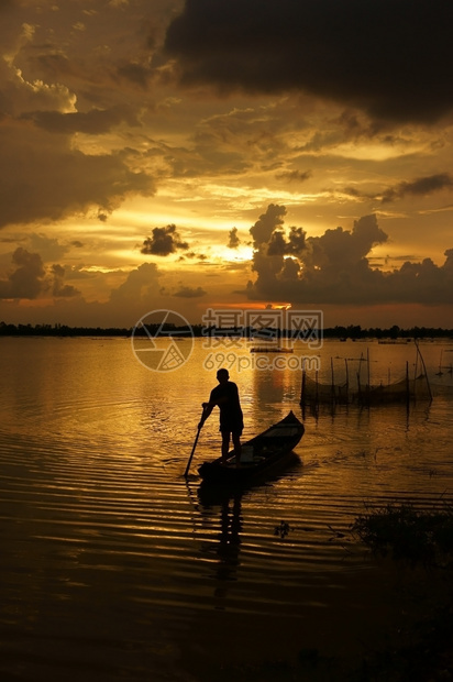 渔夫轮廓平静的人们站在划艇上日落时排船向河边的太阳前行图片