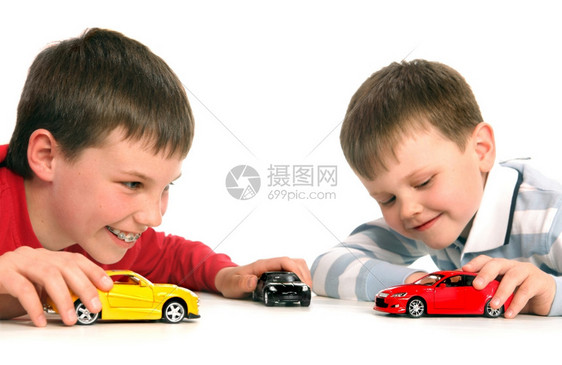 乐趣白色的两个男孩在白色背景下玩汽车事故违反图片
