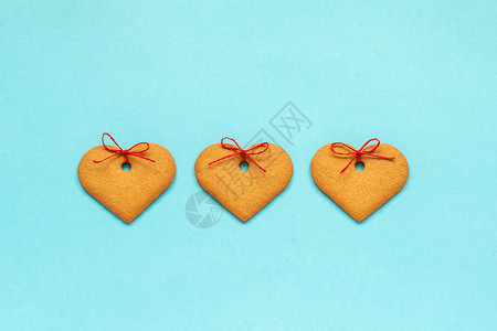 礼物可口金吉儿的心脏形状装饰在蓝背景一排列的弓上翻版空间情人卡翻版游戏曲奇的心脏形状和蓝色背景的弓翻版空间卡曲奇饼图片