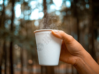 天气白色的清晨用纸杯装热饮料的手握其模糊的自然背景放松环境旅行概念假期图片
