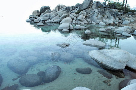 美丽的蓝色水在Tahoe清水湖和GraniteBouldders湖的一个小海湾中用浅蓝色锡罐环绕花岗岩巨石柱的清水晶体图片