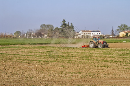 引擎重的红色拖拉机在田地上工作图片