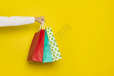 空的购物或销售概念女手握黄色背景上隔离的购物纸袋带有复制空间的横幅女手握黄色背景上隔离的购物纸袋携带买图片