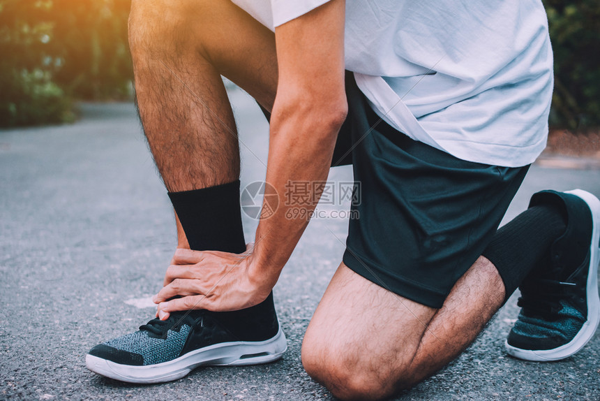 跑步者脚踝受伤在街上奔跑的男子正在去锻练运动背景的疼痛身体图片