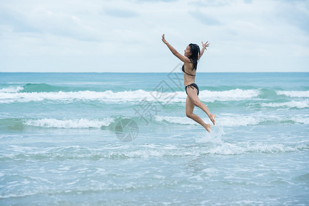 海洋女独自的黑头发棕色泳衣比基尼在海滩和浪上跳跃图片