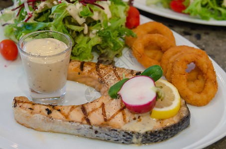 吃鲑鱼牛排和盘子里的蔬菜沙拉油炸午餐图片