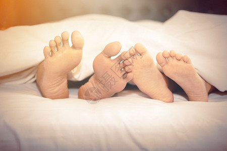 家庭在中的床上双脚露出白色的休息在室内图片