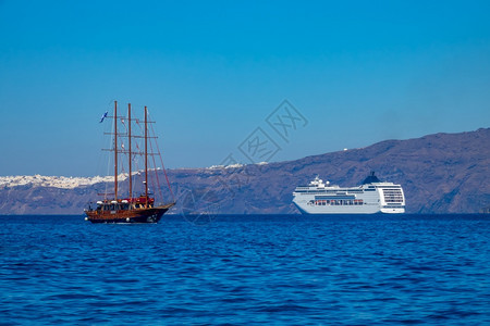 水木制的圣托里尼多头游轮和桑托里尼海岸外三重旧船现代游轮和旧帆船停靠的希腊Sunny日旅行图片