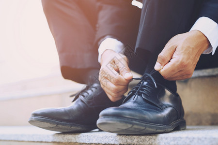 近身的商人手领带鞋穿着皮坐在楼梯背景上棕色的鞋类优雅图片