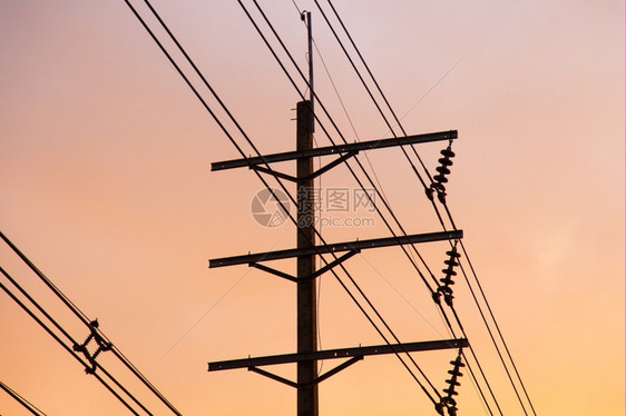 轮廓伏特工业的电线杆和在幕后是夜晚太阳的天空图片