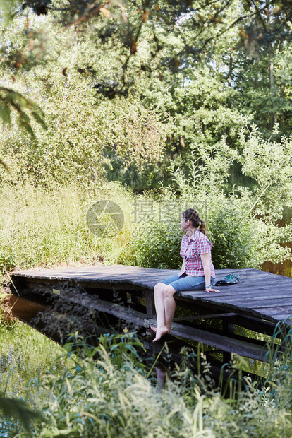 之中绿化户外在湖边的桥上坐在树丛中与自然相近暑假期间的人坎迪德人真实的时刻情况图片