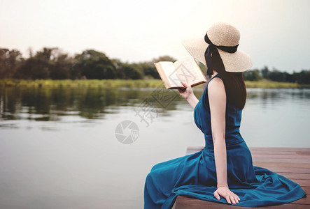 湖坐在甲板和阅读书中脱插生命概念的河滨座椅上裙子女孩图片