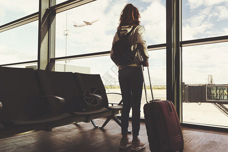 国际的登机度假旅行概念在机场古老影响背景下一名年轻女孩背着手提箱后视线等待飞机起的行李箱在机场前方冒险图片