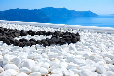 圣托里尼岛希腊Thira岛Sunny日黑石和白色块在露台海风岸白石和黑质地旅行海景图片