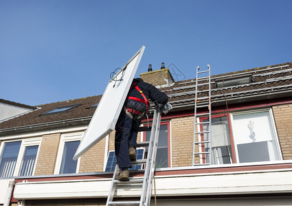 绿色男人用太阳能电池板攀登屋顶的梯子腰带在职图片