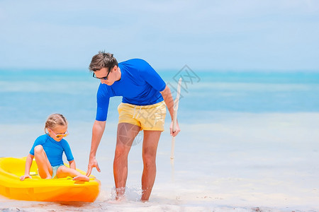 童年轻的爸父亲和小女孩在热带海滨的滩上父亲和孩子在热带海滩上家庭玩沙具图片