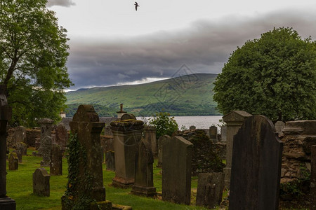 伤心帕利卡拉斯团结的在苏格兰卢斯教区堂院子里墓碑地有背景的飞鸟和湖泊在苏格兰的卢斯教区堂院子里图片