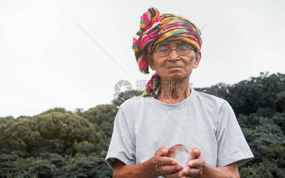 亚洲高级人手握着神奇晶玻璃球在自然背景上祷告圆形的希望美丽图片