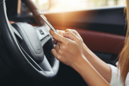 里面亚裔妇女在路上驾驶汽车使用智能手机在路上女事故图片