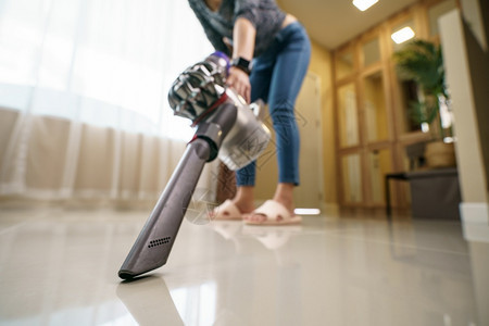 妇女在地板上使用真空吸尘清洗常设服务灰尘图片