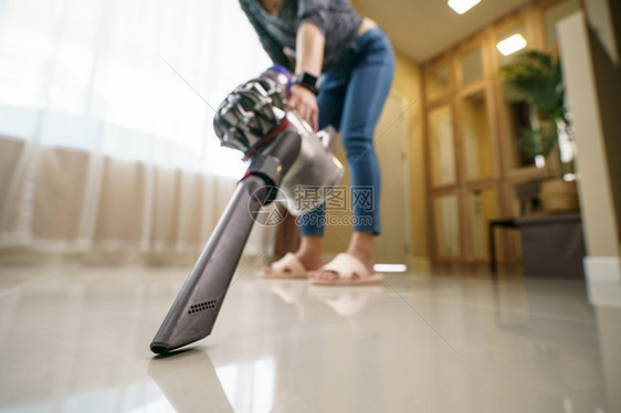 妇女在地板上使用真空吸尘清洗常设服务灰尘图片