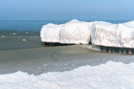 海浪在冰冷的雪泥中在海的防波堤上结冰在冬天的海岸中防波堤上冰在冷雪泥中海浪在冬天岸白色景力量图片