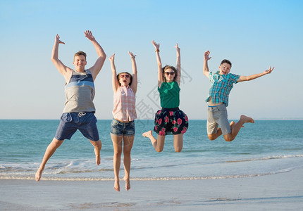 旅行逃脱跳跃一群快乐的年轻朋友在海滩上玩得开心在日落时一起跳来图片