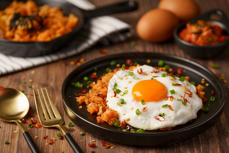 金奇炒米饭加煎鸡蛋和新鲜的香菜卷心碗里配满了木制背景的韩国菜风格健康桌子辛辣的图片