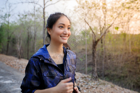 亚洲女在公园街上慢跑时笑和快乐美丽的秋天微笑图片