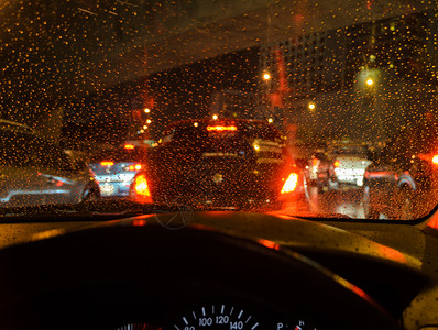 街道夜间下雨时在湿风屏上看到蓝色驾驶车散景交通图片素材