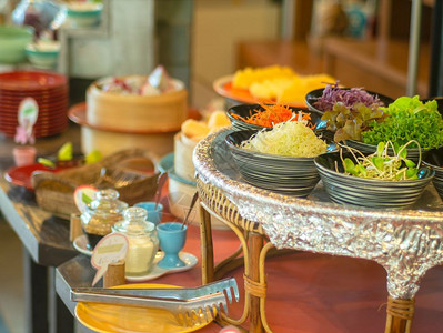 碗中的蔬菜沙拉用木制餐盘和另外一份早餐食品作为旅馆客人准备好的颜色叶子图片