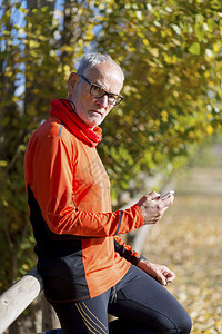退休运动具有智能手机的自然界高级跑手运动服图片