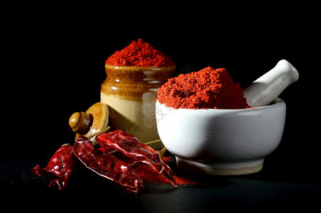 香料胡椒红辣粉用迫击和粘土锅粉碎黑色底有红辣椒粉辛的图片