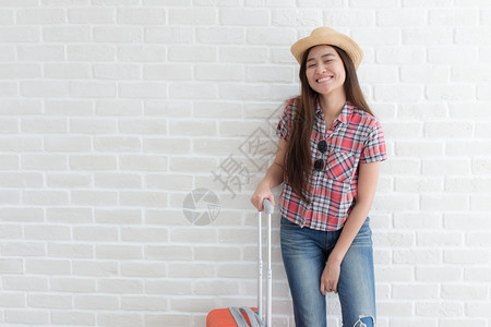 手提箱亚裔妇女准备搭乘白砖墙生活方式与旅游行Twitter微笑漂亮的图片