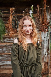 女士顺势疗法舱站在老小屋前挂上一些枯萎的草药品种年轻女子肖像孩穿着绿色衣服看摄像机笑声图片