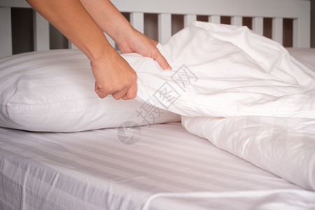 人类工亚麻布家庭主妇在旅馆换床单的手掌图片