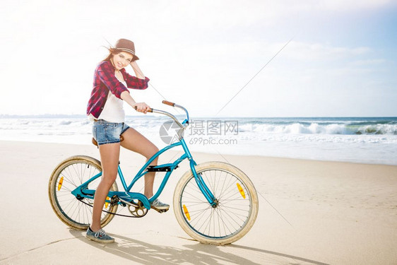 女快乐的美丽年轻女子骑自行车在海滩的上女孩图片