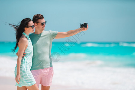 自画像在海滩上快乐的一家人拿自拍快乐的一对情侣在蜜月度假时白海滩拍照服用旅行图片