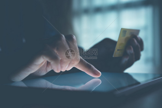 男利用平板电脑和进行网上交易的男子在使用平板电脑并进行在线交易网上购买信用卡手电子的图片