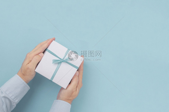 给予惊喜手握礼品箱蓝弓在色背景上方有手纸空间复制件平面情人节图片