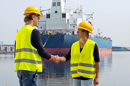 货物在工业港口的一艘大型货船面前雌海燕与男同事握手在一家大型货船前男人对讲机图片