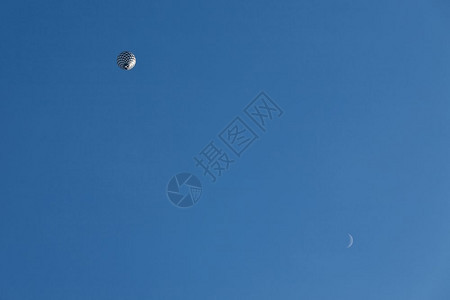 夏天飞行和月亮中的黑白气球从下方观测到蓝色天空中和月光观察到黑色和白气球骑颜图片