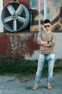 身穿蓝牛仔裤的白人年轻英俊成男子站在砖墙前生时尚走图片