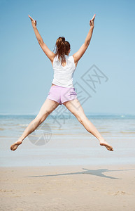 蓝色的玩青年美丽精力充沛年轻女子在海滩上跳跃图片