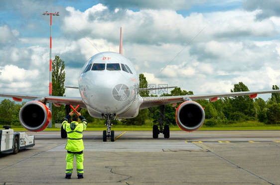 引擎宽的身体男子在停机坪上用红色棍子给飞机标志运输图片