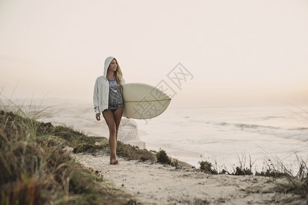 海岸行走的女冲浪者图片